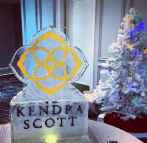 Kendra Scott holiday event ice sculpture in the shape of the logo on a pedestal with Kendra Scott etched on it by Full Spectrum Ice Sculptures