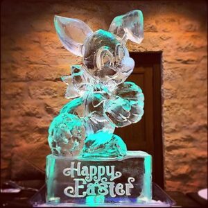 Easter Bunny shaped ice sculpture sitting on a pedestal with Happy Easter etched on it by Full Spectrum Ice Sculptures