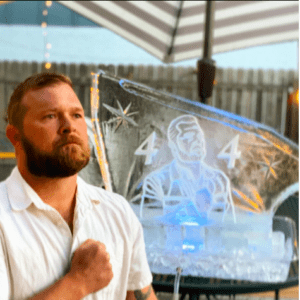 Man standing in front of ice sculpture shot block carved with an image of himself and 44