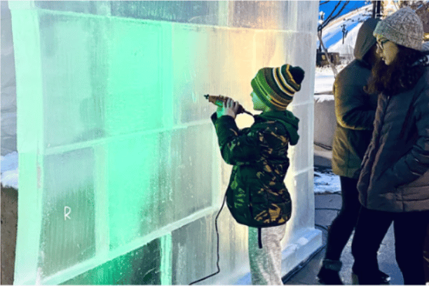 wall of ice with boy carving into the side